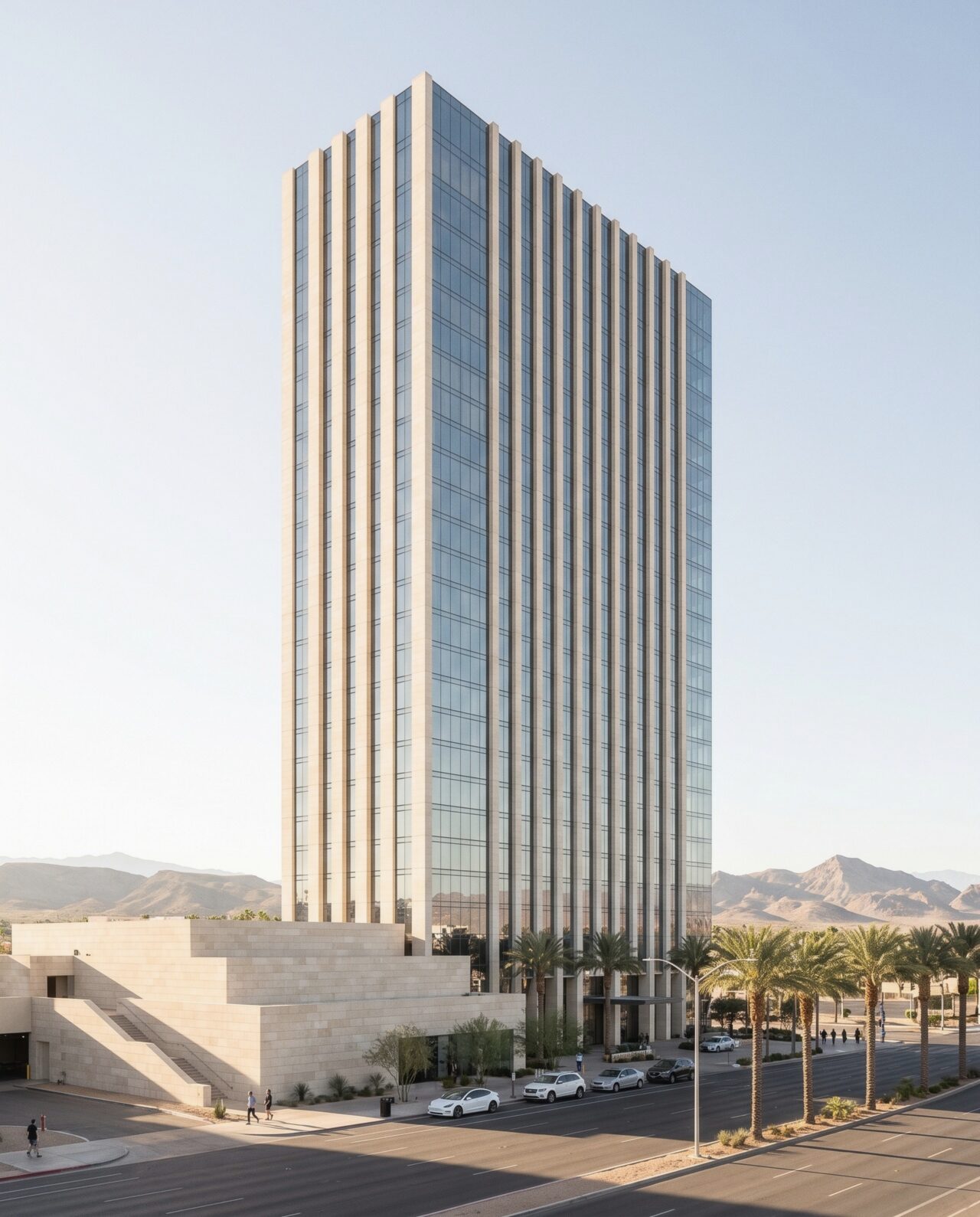 The Kona Las Vegas tower, a slender slab of pale limestone fins and blue-grey glass, seen across a wide boulevard with a few pedestrians, in afternoon sun with mountains behind.