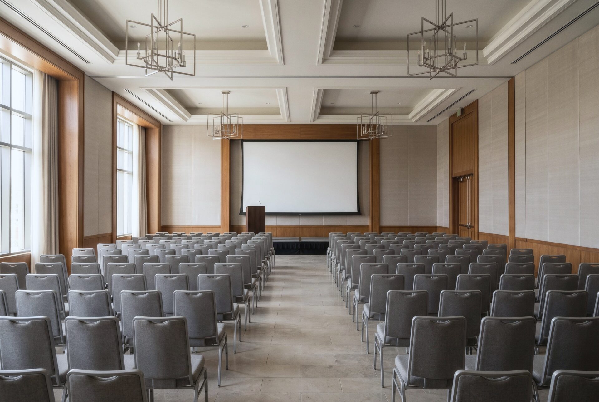 The Palm Ballroom set theater style with rows of grey chairs facing a stage, a screen, and a lectern.