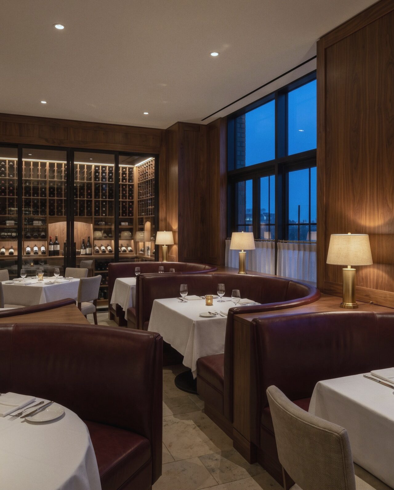 The Ember & Salt dining room with walnut paneling, deep red leather booths, and a glass-walled wine room.