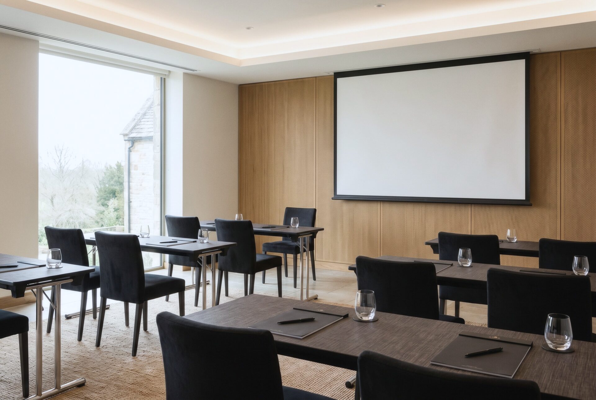 A Tide Room breakout set classroom style for about twenty, with dark tables, black chairs, and a wall screen.